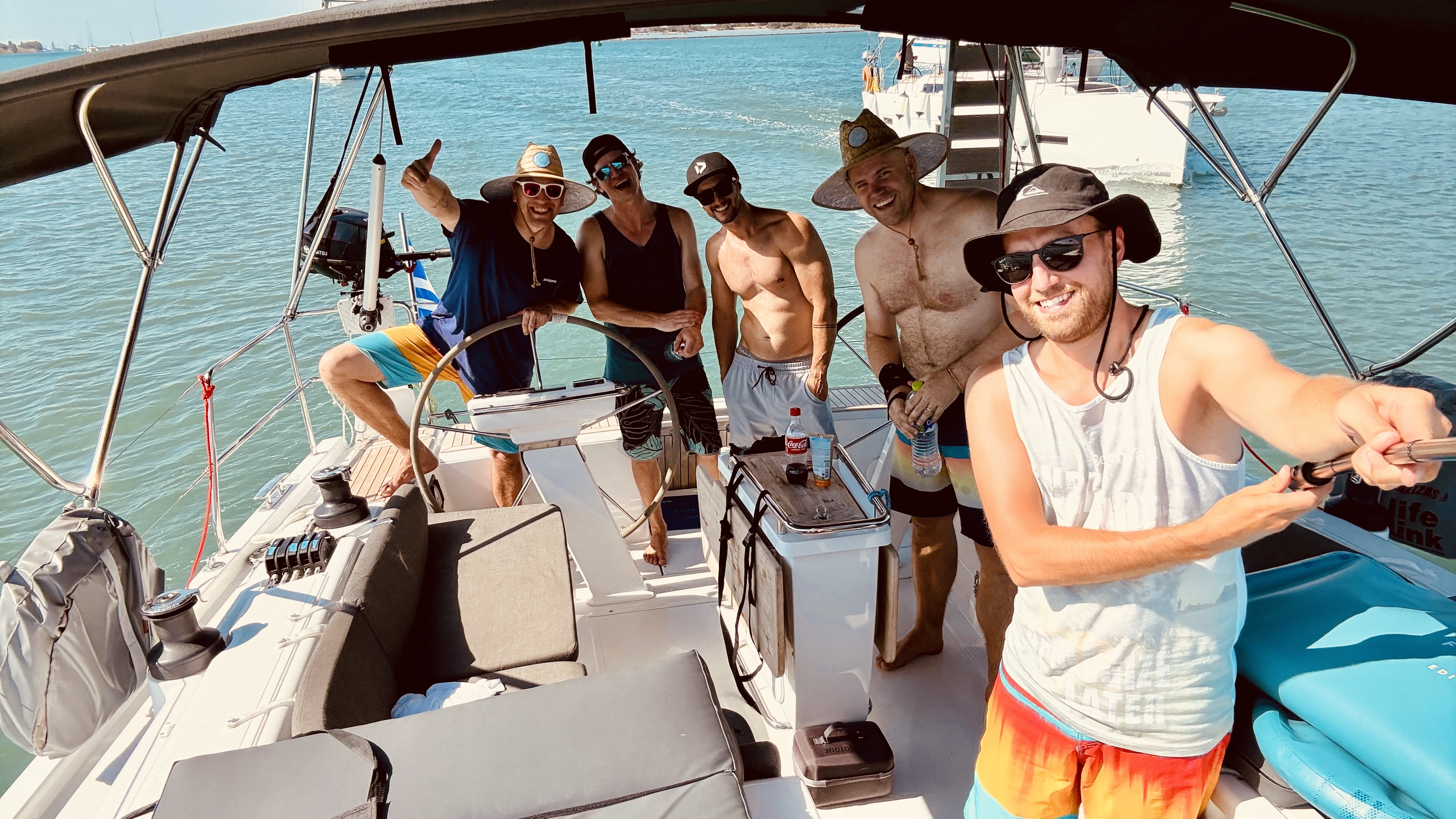 Eine junge Windbeutel-Crew auf einer Segelyacht vor einer türkisblauen Bucht